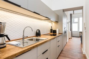 Eine moderne Küche mit einer Holzarbeitsplatte, einem Edelstahlspülbecken und einer backsplash aus sechseckigen Fliesen.