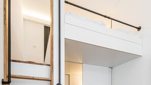 En modern inredning med en trästege, en grå fåtölj och ett glasbord.