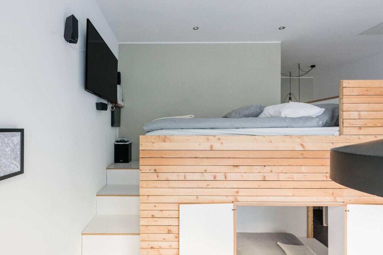 Ein schlicht eingerichtetes Schlafzimmer mit Etagenbett, einem an der Wand befestigten Flachbildfernseher und einer gerahmten Karte.