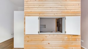 Una habitació amb parets de fusta, un llit i una porta blanca.