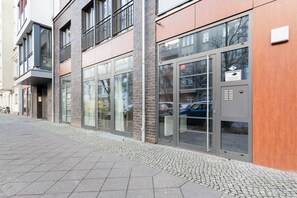 Ein modernes Gebäude mit großen Glasfenstern, einem Metalltor und einem gepflasterten Gehweg.