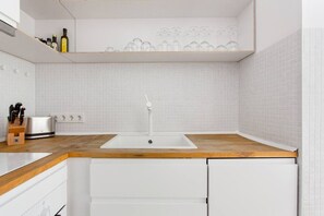 Eine moderne Küche mit weißem Spülbecken, einer Holz Arbeitsplatte und weißen Schränken.