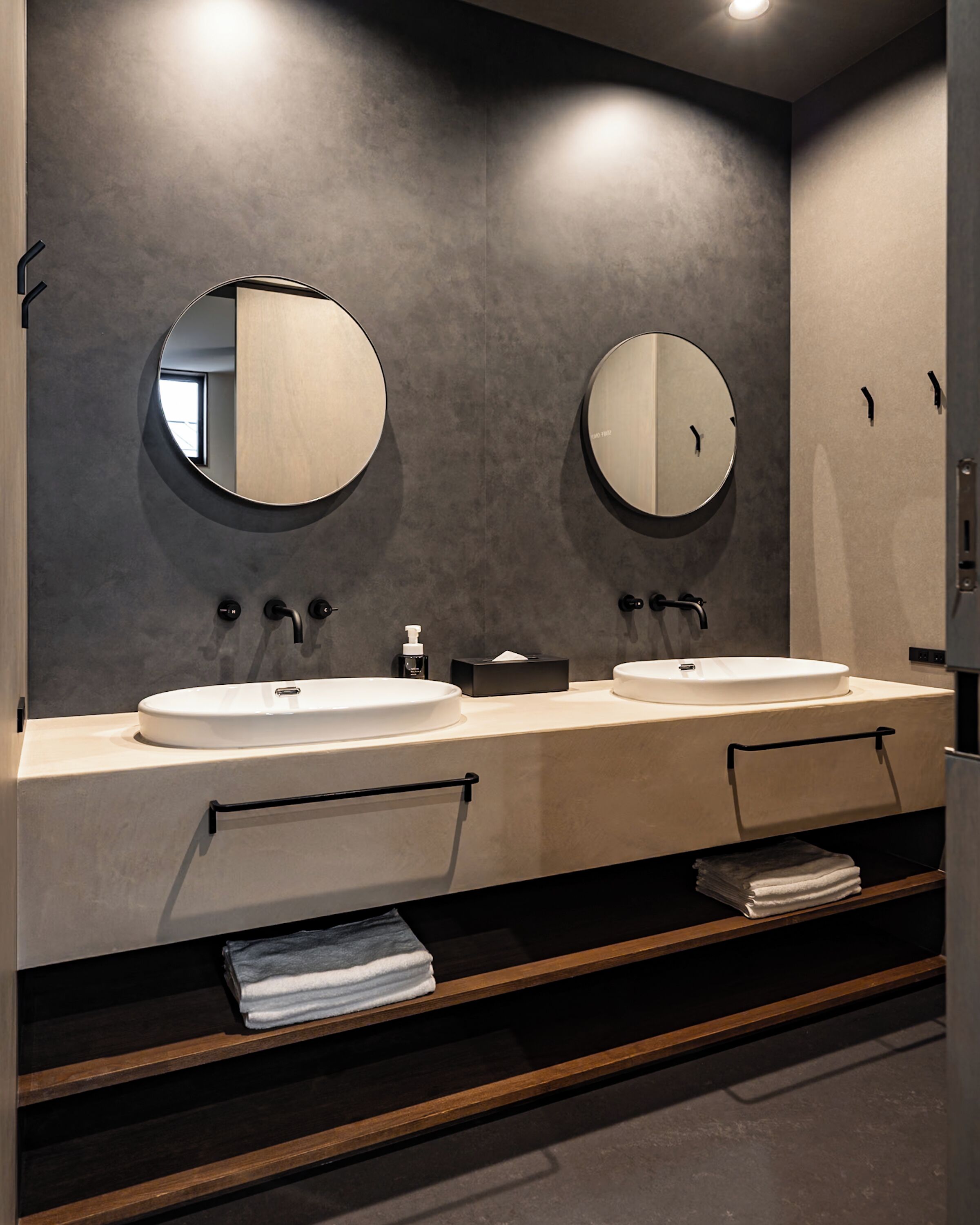 Un baño moderno con dos lavamanos, un espejo y un perchero para toallas.