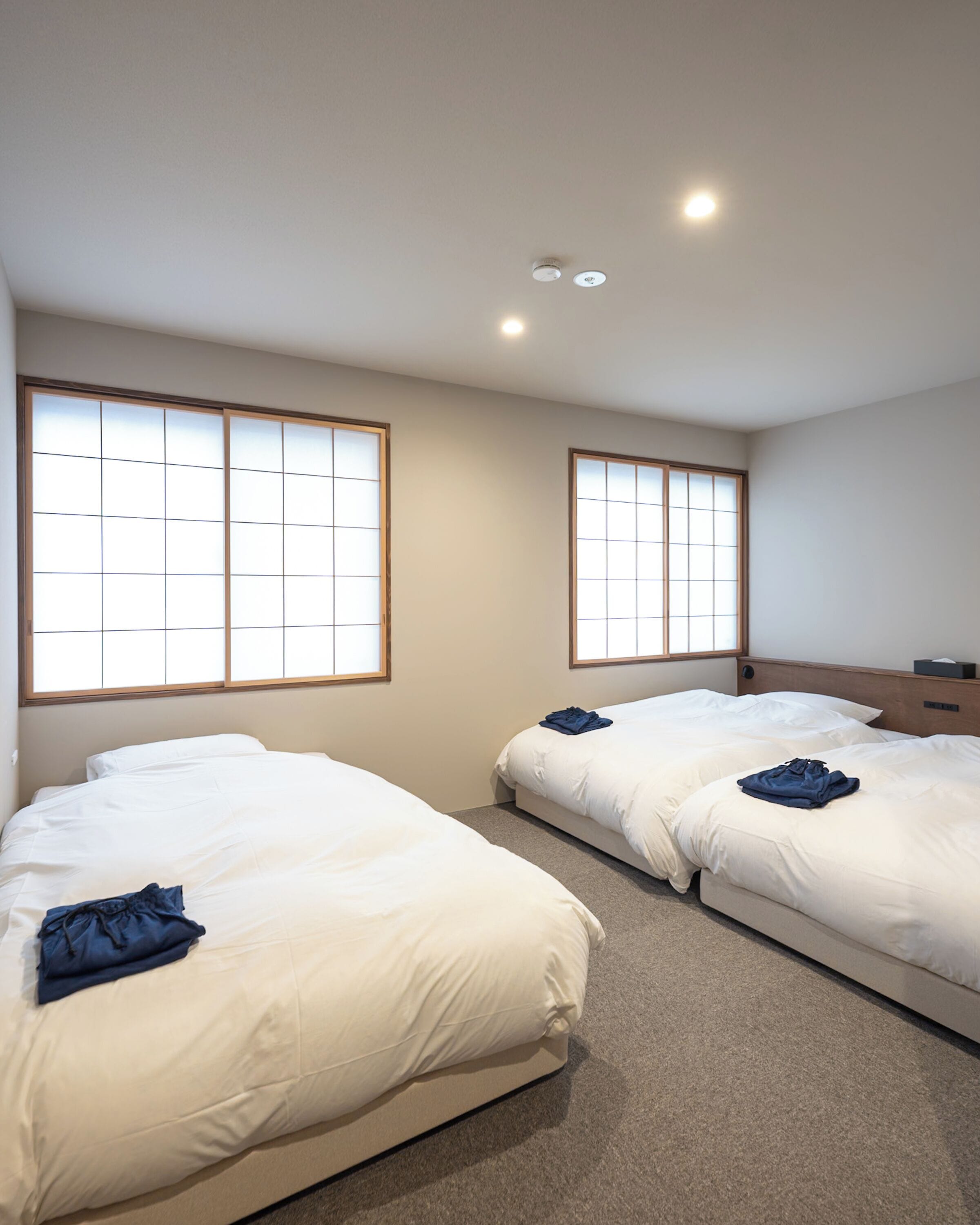 A hotel room with two beds, a wooden headboard, and large windows with a grid pattern.