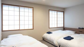 A hotel room with two beds, a wooden headboard, and large windows with a grid pattern.