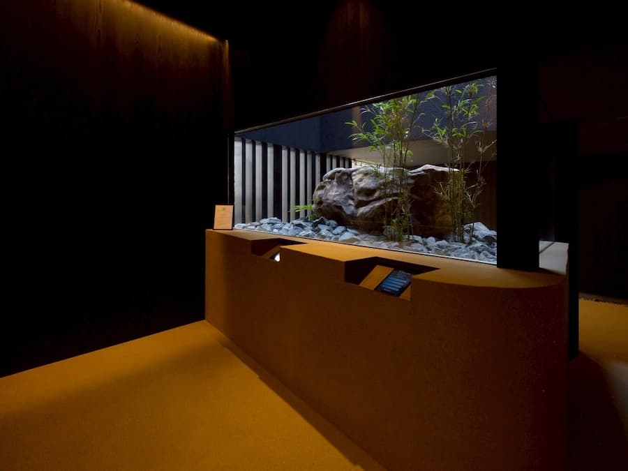 Una habitación moderna con un acuario grande, un banco de madera y un televisor montado en la pared.