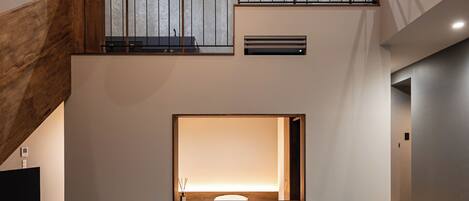 Un interior moderno con un amplio espacio de estar, una escalera y un techo alto con iluminación empotrada.