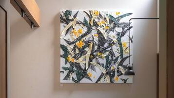 Un interior moderno con diseño minimalista, que incluye un armario de madera, un sofá gris, una mesa redonda y un cuadro abstracto colgado en la pared.