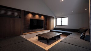 Una sala de estar moderna con una televisión de pantalla plana, una mesa de centro y un sofá con vistas al exterior.