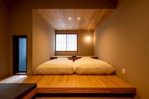 A room with a wooden slatted ceiling, a bed with two pillows, a window with vertical blinds, and a small bedside table. - TOVILLA STAY Niigata Honcho (Niigata-shi, Chuo-ku)