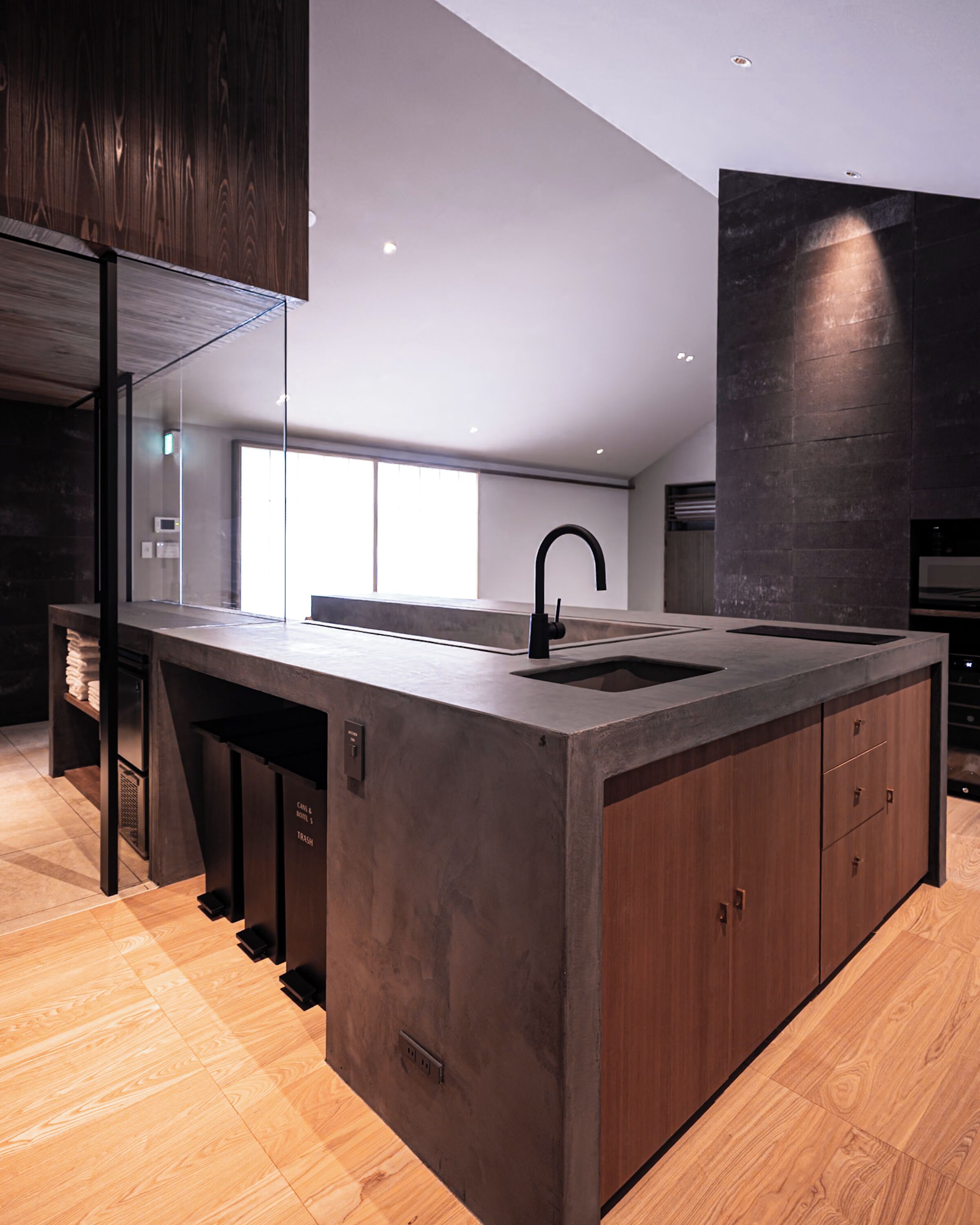 A modern kitchen with a large island, built-in appliances, and a dark wood finish.