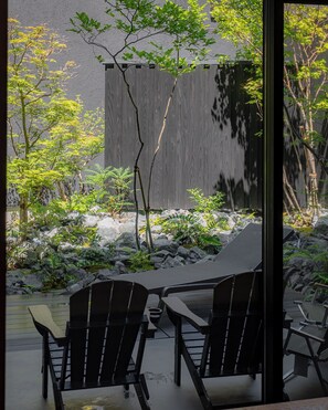 A modern outdoor seating area with two chairs and a table, surrounded by rocks and greenery. - TOVILLA STAY Niigata Honcho (Niigata-shi, Chuo-ku)