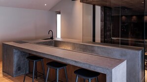 Una cocina moderna con una isla central, taburetes de bar y un ventanal grande.