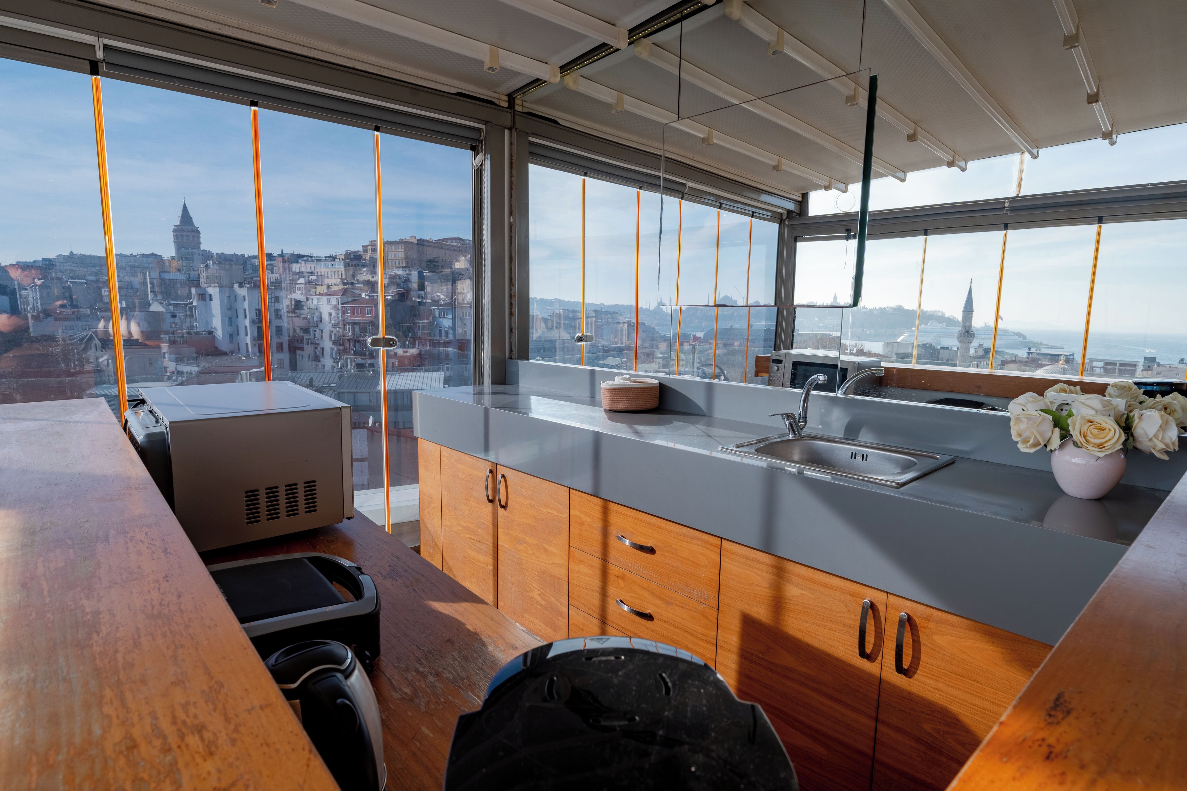 A modern kitchen with a large window, wooden cabinets, a sink, and a countertop.