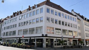 Un edificio de varios pisos con espacio comercial en la planta baja, ventanas amplias y techo plano.