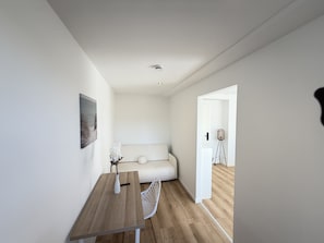 Et minimalistisk rum med et træbord, en hvid sofa og en lille hvid stol.