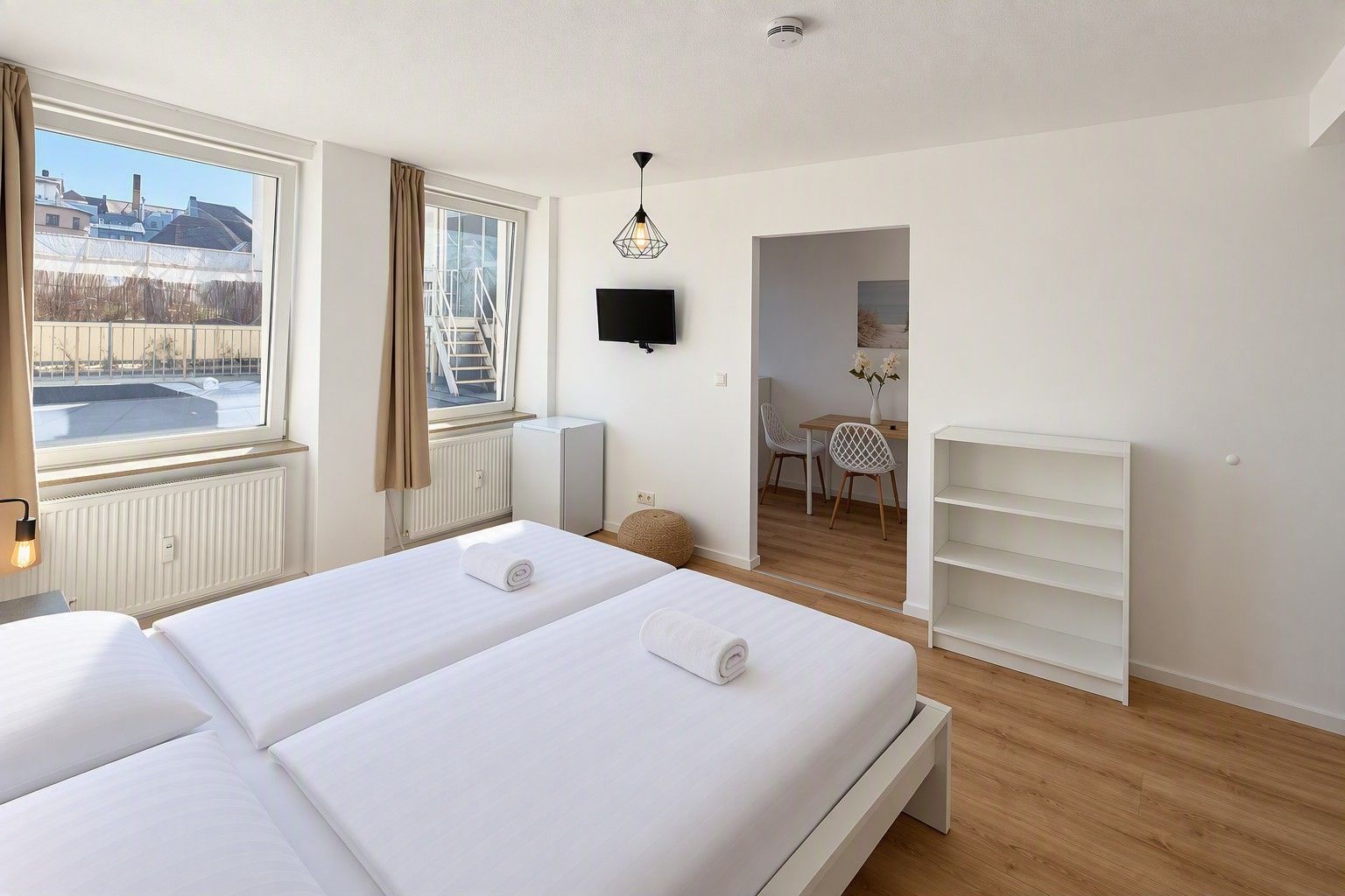 Ett hotellrum med två sängar, ett element, en tv, ett litet bord med stolar och utsikt över omgivningarna.