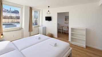 Ett hotellrum med två sängar, ett element, en tv, ett litet bord med stolar och utsikt över omgivningarna.