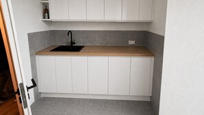 Una cocina con armarios blancos, un lavamanos negro y una encimera de madera.