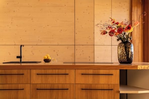 Eine Küche mit Holzausstattung, einem schwarzen Wasserhahn und einer Vase mit Blumen auf der Arbeitsplatte.