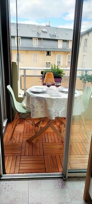 Ein Balkon mit Tisch für zwei Personen, einem Stuhl und einem Blumentopf.