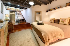 Ein Schlafzimmer mit einem Bett, einer Treppe, einem Spiegel und einem Bücherregal.