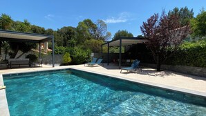 A rectangular swimming pool with clear water, surrounded by lounge chairs and a covered seating area. - "Le BEL AIR" House with pool, AC, and Wi-Fi—Near the ocean (La Ciotat)