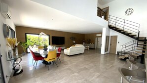A spacious living area with a dining table, sofa, and staircase. - "Le BEL AIR" House with pool, AC, and Wi-Fi—Near the ocean (La Ciotat)
