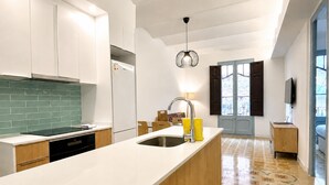Une cuisine moderne avec des meubles blancs, un crédence vert, un lave-vaisselle encastré et un grand îlot central doté d’un évier.