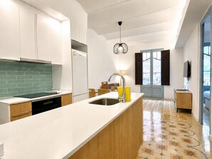 Eine moderne Küche mit weißen Schränken, einer grünen Rückwand, einem eingebauten Geschirrspüler und einer großen Kochinsel mit Spüle.