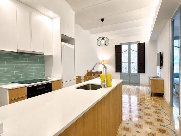 Une cuisine moderne avec des meubles blancs, un crédence vert, un lave-vaisselle encastré et un grand îlot central doté d’un évier.