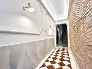 Ein Flur mit kariertem Boden, weißen Wänden und einer Backsteinwand.