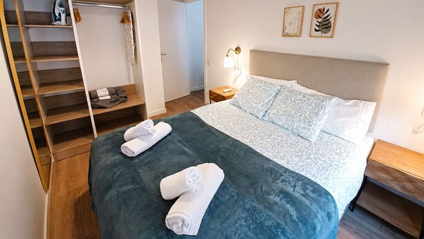 Una camera d'albergo con un letto, un armadio, una scrivania e un comodino.