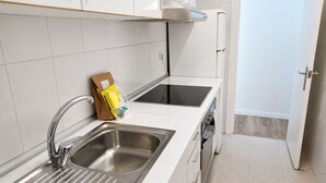 Una cucina moderna con lavelli in acciaio inossidabile, forno integrato e piano di lavoro bianco.
