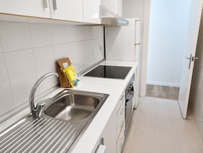 Eine moderne Küche mit Edelstahlspülen, einem eingebauten Ofen und einer weißen Arbeitsplatte.