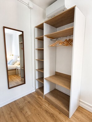 A walk-in closet with open shelving, a mirror, and a hanging rod. - CC62 Apartamento Sagrada Familia de Barcelona (Barcelona)