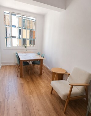 A room with a wooden dining table, four chairs, a small round table, and a single chair. - CC52 Apartamento con balcón cerca Sagrada Familia (Barcelona)