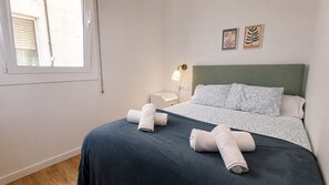 Ein Schlafzimmer mit Bett, Kissen, einem Nachttisch, einer Lampe und zwei Wandbildern.