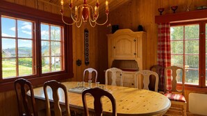 Een houten eetkamer met een kroonluchter, een groot raam en een kast.