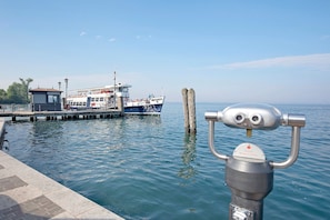 Blick auf das Wasser mit einer Anlegestelle, einem Boot und einer Metallkonstruktion mit Fernglas.