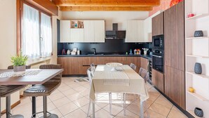 Una cucina moderna con travi in legno, un'area pranzo con tavolo e sedie, ed elettrodomestici integrati.