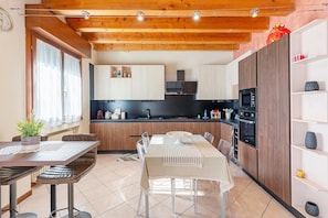 Une cuisine moderne avec des poutres en bois, un coin repas avec une table et des chaises, et des appareils électroménagers intégrés.