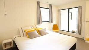 A modern hotel room with a large bed, a small side table, a chair, and a large window with curtains. - Cube Magnifique 8 (Nijkerk)