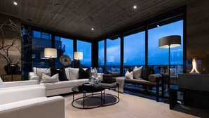 Una sala de estar moderna con chimenea, ventanas amplias y una zona de estar acogedora.