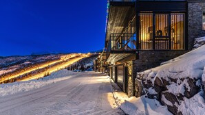 Una carretera nevada que conduce a un edificio con ventanas amplias y un balcón.