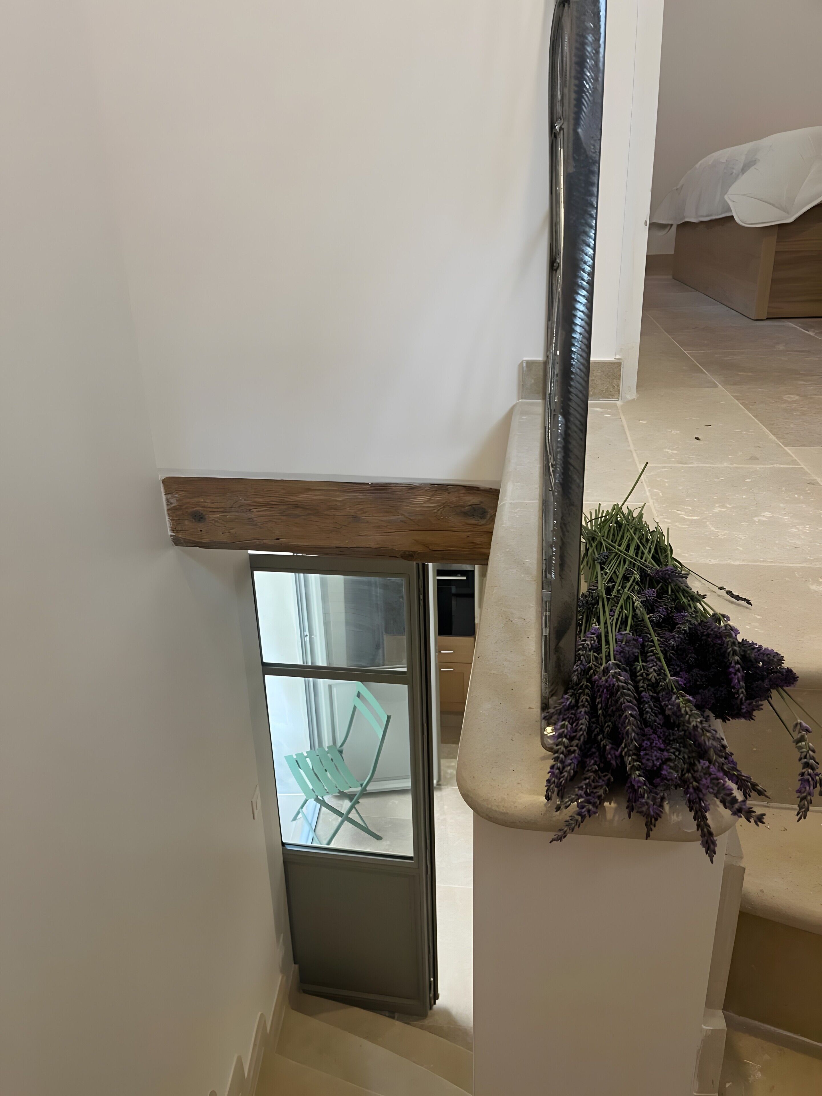 Eine Treppe mit Holzgeländer, einer Glastür und einem Lavendelstrauch.