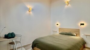 Ein Schlafzimmer mit Dachfenster, einem Bett, einem Sessel und zwei Wandleuchten.