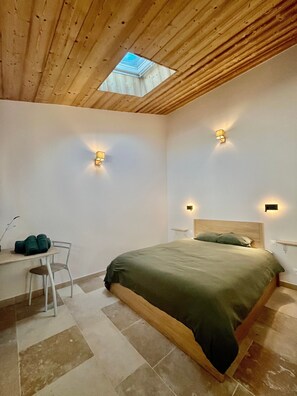 Een slaapkamer met dakraam, een bed, een stoel en twee wandlampen.