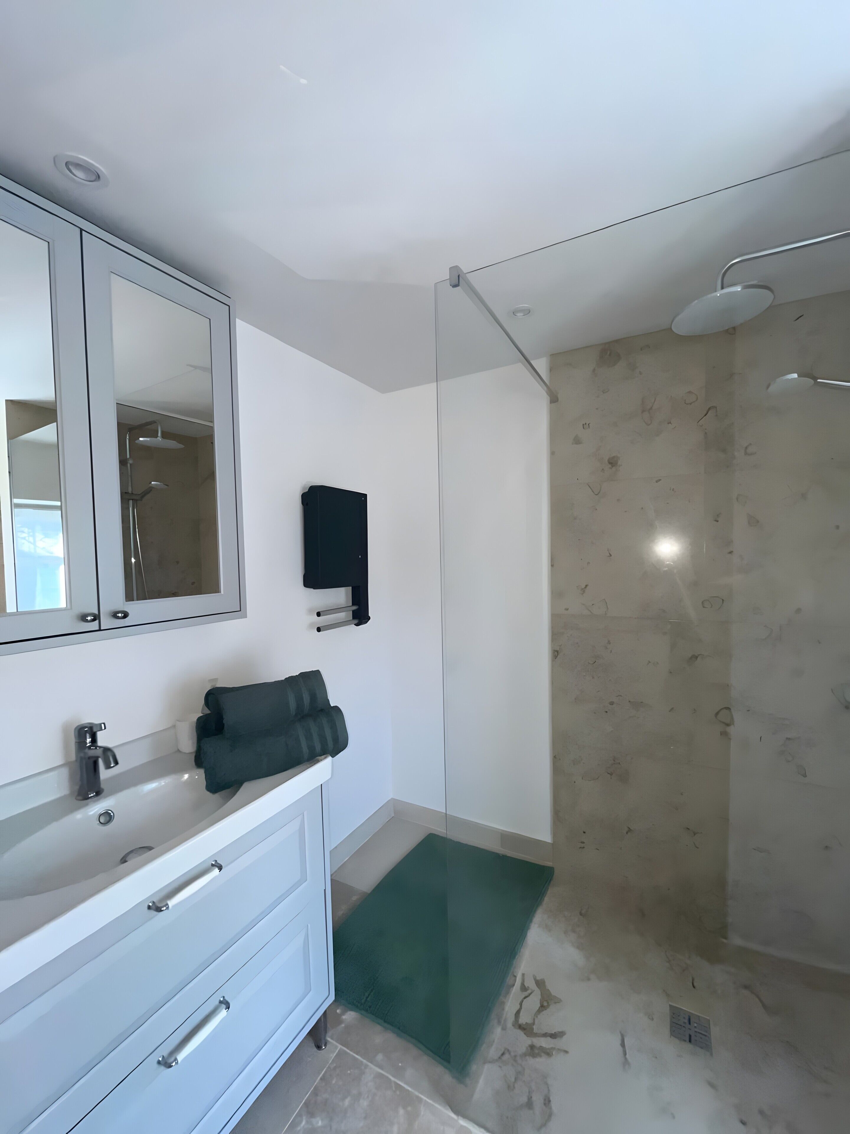 Une salle de bain équipée d’un miroir, d’un lavabo, d’un porte-serviettes et d’une douche.