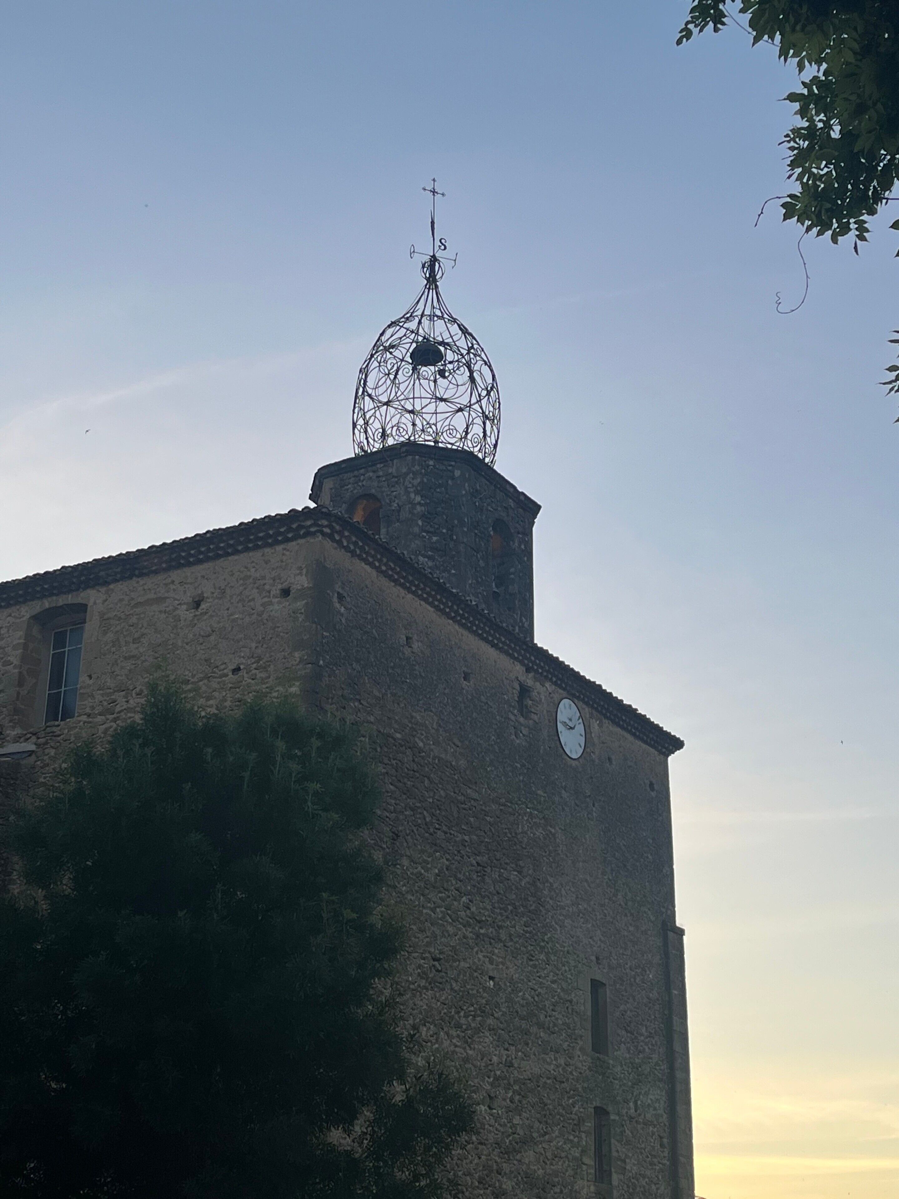 A building with a stone facade, a clock, and a decorative metal structure on top.